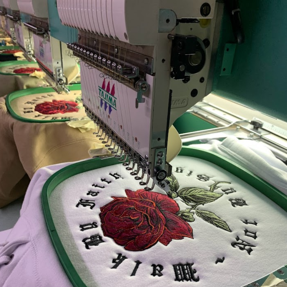 Embroidery machine stitching a large rose design on fabric