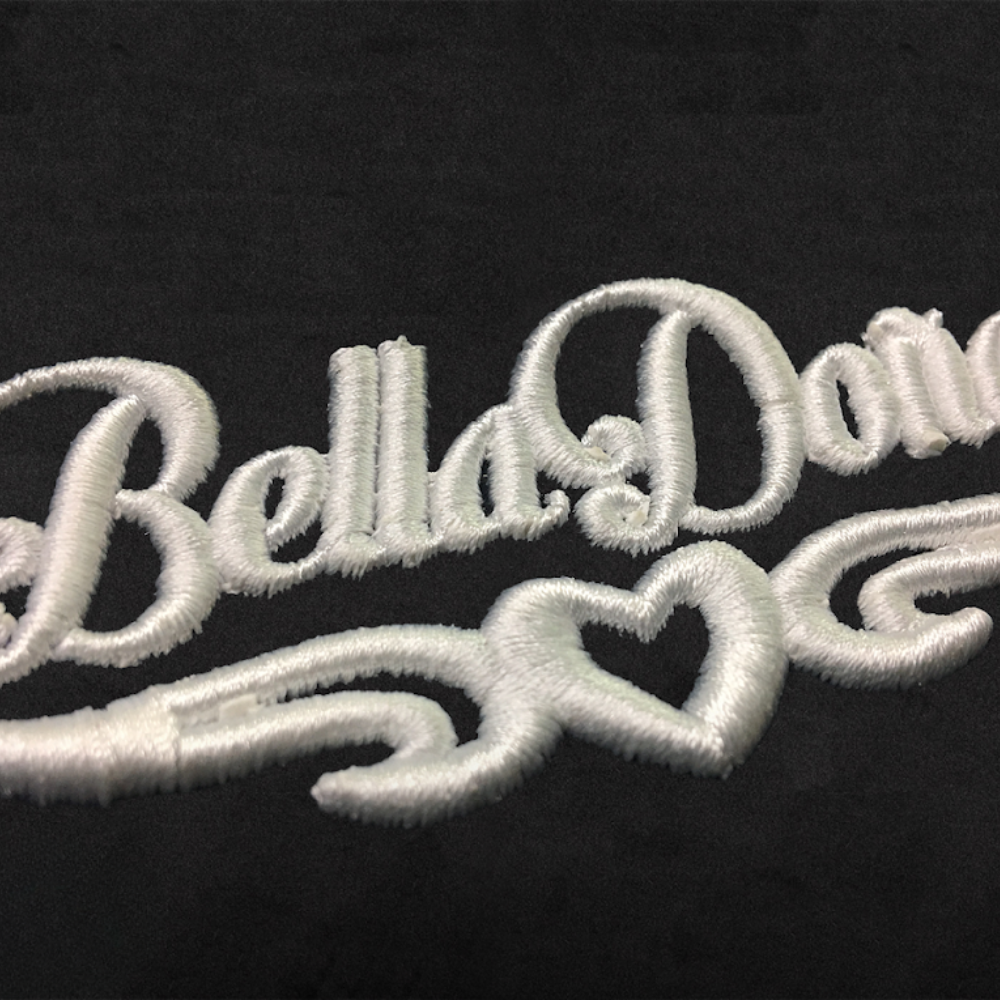 Close-up detail of white script embroidery on black fabric