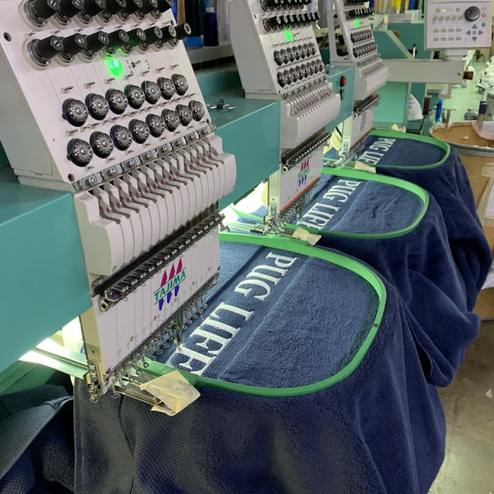 Embroidery machines stitching lettering onto blue towels